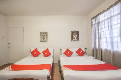 two beds in a room with red and white pillows at OYO 588 Sunrock Resort in Antipolo