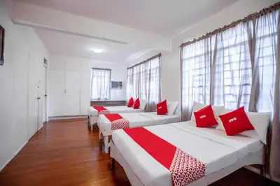 three beds in a room with red and white pillows at OYO 588 Sunrock Resort in Antipolo