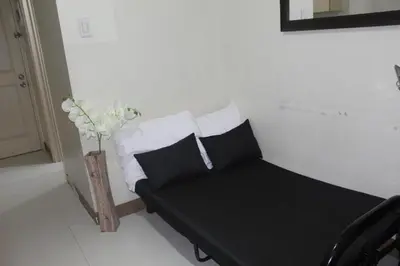 a room with a couch with pillows and a vase at Chateau Elysee a2 near Airport,Wifi Netflix Kitchen in Manila