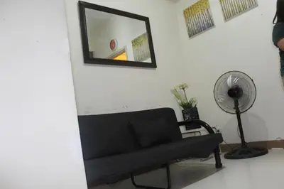 a living room with a black couch and a mirror at CHATEAU ELYSEE A10 near airport in Manila