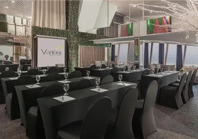 a restaurant with black tables and chairs and a screen at Vivere Hotel and Resorts in Manila
