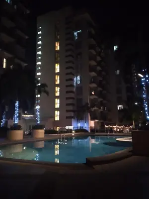 a swimming pool at night with tall buildings at One Palm Tree Villas-Terminal 3 Pasay Manila in Manila