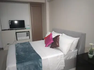 a bedroom with a bed with pillows and a tv at One Palm Tree Villas-Terminal 3 Pasay Manila in Manila