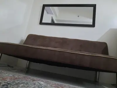 a brown couch in a room with a mirror at Green Residence 23rd Floor in Manila
