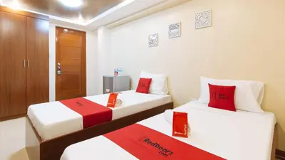 two beds in a room with red pillows on them at RedDoorz Plus near Uptown BGC Mall in Manila
