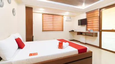 a bedroom with a large bed with red pillows at RedDoorz Plus near Uptown BGC Mall in Manila