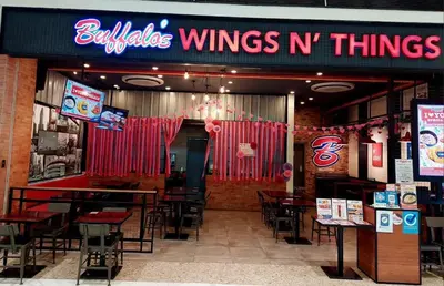 a restaurant with tables and chairs and a sign that reads bottles wings n things at 1BR Jazz Bel-air Makati, POOLVIEW, TRIDENT in Manila