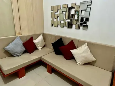 a couch with four pillows on it with a painting at 1BR Jazz Bel-air Makati, POOLVIEW, TRIDENT in Manila