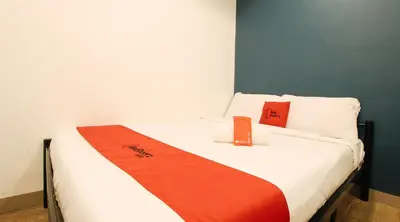 a bed with an orange and white blanket on it at RedDoorz Plus @ San Marcelino Malate in Manila