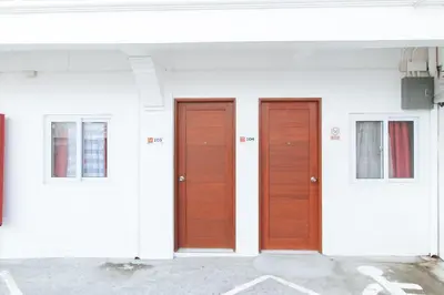three brown doors on a white building at RedDoorz near Mercado del Lago in Manila