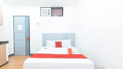 a bedroom with a white bed with a red blanket at RedDoorz at CAA Road Las Pinas in Manila