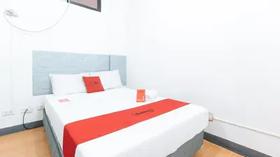 a bedroom with a bed with red and white sheets at RedDoorz at CAA Road Las Pinas in Manila