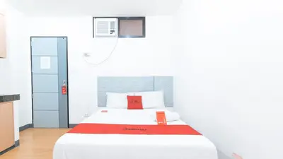 a bedroom with a white bed with a red blanket at RedDoorz at CAA Road Las Pinas in Manila
