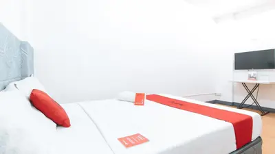 a white bed with red pillows on it in a room at RedDoorz at CAA Road Las Pinas in Manila