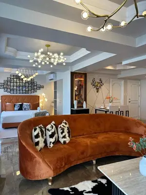 a living room with a brown couch and a bed at City View at MAKATI Prime Luxury in Manila