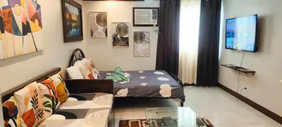 a room with a bed and a couch and a tv at Centropolis King Bed Deluxe in Manila