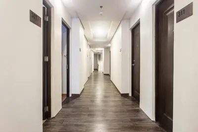 a hallway with white walls and wooden floors and doors at Airo Hotel Manila in Manila