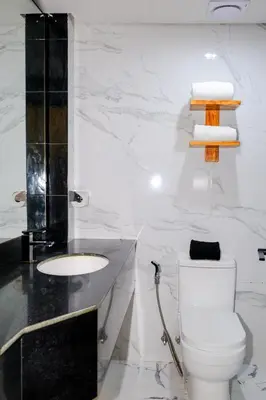 a white bathroom with a toilet and a sink at Airo Hotel Manila in Manila