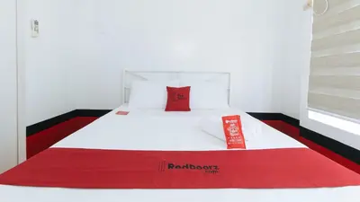 a red and white bed with a red pillow on it at RedDoorz at The Providence Tower in Manila
