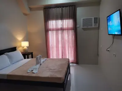 a bedroom with a bed and a tv and a window at G Square Residences in Manila