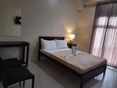 a small bedroom with a bed and a chair at G Square Residences in Manila