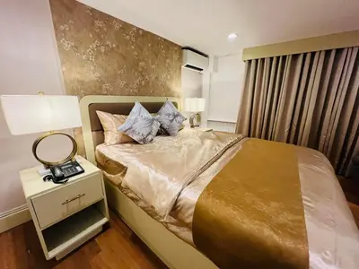 a bedroom with a bed and a lamp on a night stand at Arzo Hotel Manila in Manila