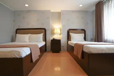 a bedroom with two beds and a nightstand between them at Arzo Hotel Manila in Manila
