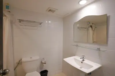 a white bathroom with a toilet and a sink at Arzo Hotel Manila in Manila