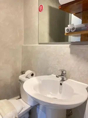 a bathroom with a sink and a toilet and a mirror at Anex Hotel in Manila