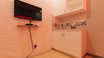 a room with a tv on a brick wall with a cabinet at RedDoorz near Christ the King Medical Center in Manila