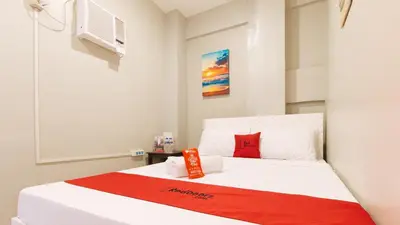a bedroom with a white bed with a red blanket at RedDoorz near Christ the King Medical Center in Manila