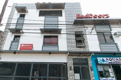 a white building with a red sign on it at RedDoorz near Christ the King Medical Center in Manila