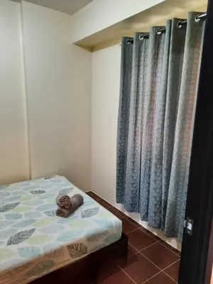 a small bedroom with a bed and blue curtains at The Rochester in Manila