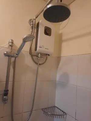 a shower with a shower head on a wall at The Rochester in Manila