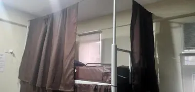 a bedroom with a bed and a window with a curtain at Snoozeph in Manila