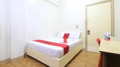 a bedroom with a white bed with a red ribbon on it at RedDoorz Plus @ Chinatown Binondo in Manila