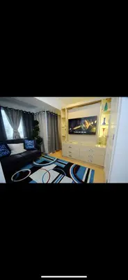 a living room with a television and a large rug at The Rustic Haven-1 in Manila