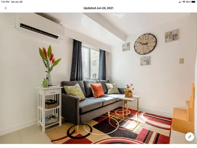 a living room with a couch and a clock on the wall at The Rustic Haven-1 in Manila