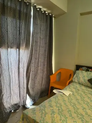 a bedroom with a bed and a window with a chair at Favila Condotel Unit-150 Newport Boulevard near Airport Terminal 3 and all other Airport in Manila