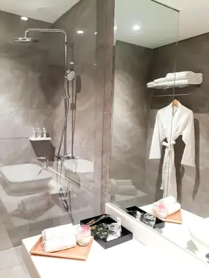 a bathroom with a mirror and a robe on a mannequin at The Excelsior Hotel Las Piñas in Manila