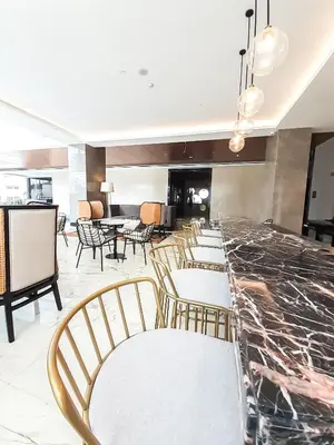 a lobby with chairs and a bar with a table at The Excelsior Hotel Las Piñas in Manila