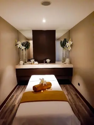 a bedroom with a bed with a yellow blanket and flowers at The Excelsior Hotel Las Piñas in Manila