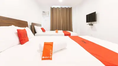 two beds in a hotel room with a tv at RedDoorz near Zobel Roxas St in Manila