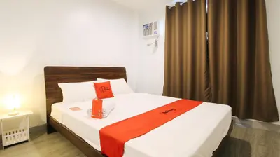 a bedroom with a bed with an orange blanket on it at RedDoorz near Zobel Roxas St in Manila