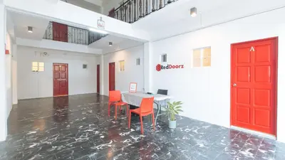 a room with a table and chairs and a red door at RedDoorz at VCloud Hills near De La Salle Dasmarinas Cavite in Dasmariñas