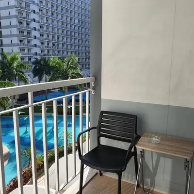 a black chair sitting on a balcony with a view of the pool at SHELL RESIDENCES in Manila