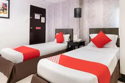 two beds in a hotel room with red pillows at Orange Nest Hotel in Manila