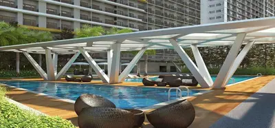 a large pool with chairs and a large building at Fame Residences T1 Family Suite 1507 in Manila