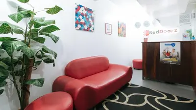 a red chair in a waiting room with a plant at RedDoorz near Pasay Rotonda in Manila