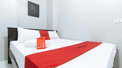 a white bed with a red blanket on it at RedDoorz near Pasay Rotonda in Manila